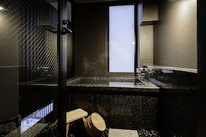 A modern bathroom with a large window, a sink, and a shower area.