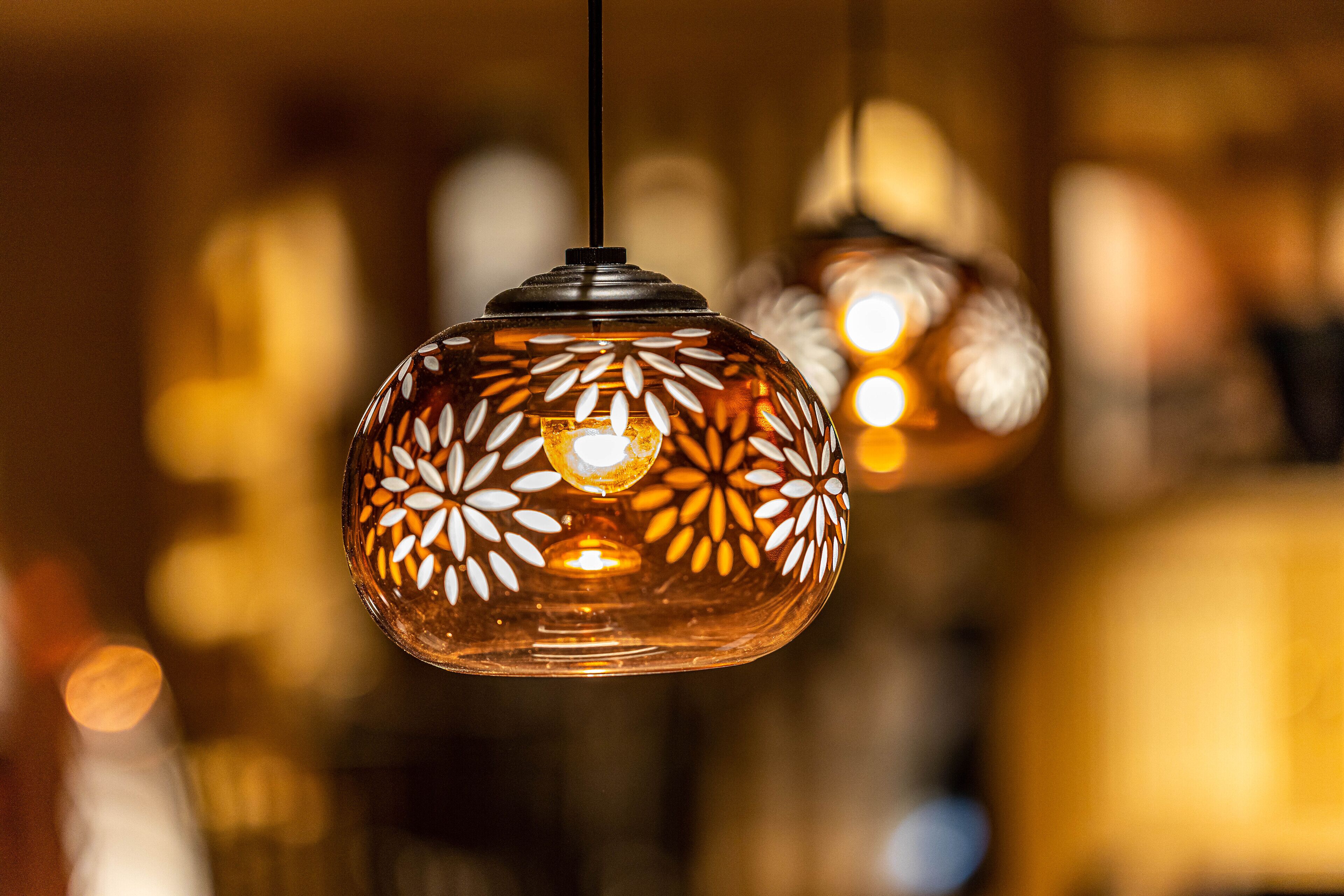 A close-up of a hanging pendant light with a floral pattern.