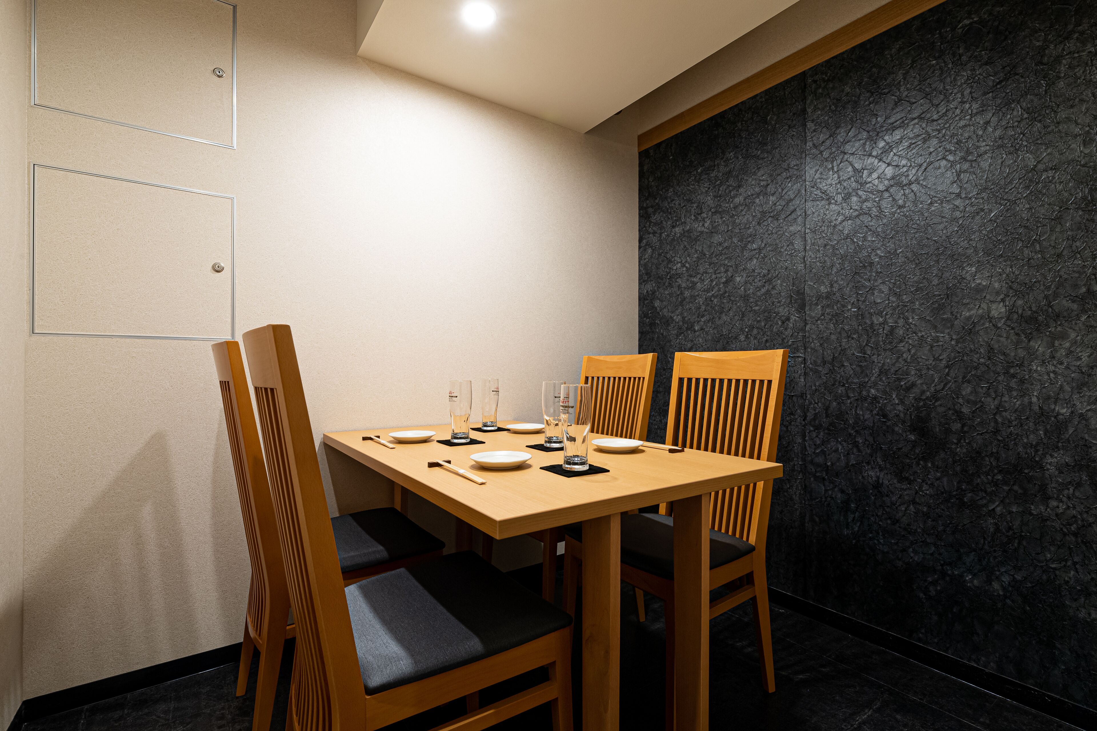 A dining area with a wooden table set for four, including plates, glasses, and cutlery.