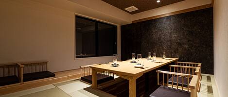 A traditional Japanese-style room with tatami flooring, a low wooden table, and built-in seating.