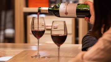 A person pouring wine into two glasses on a wooden table.