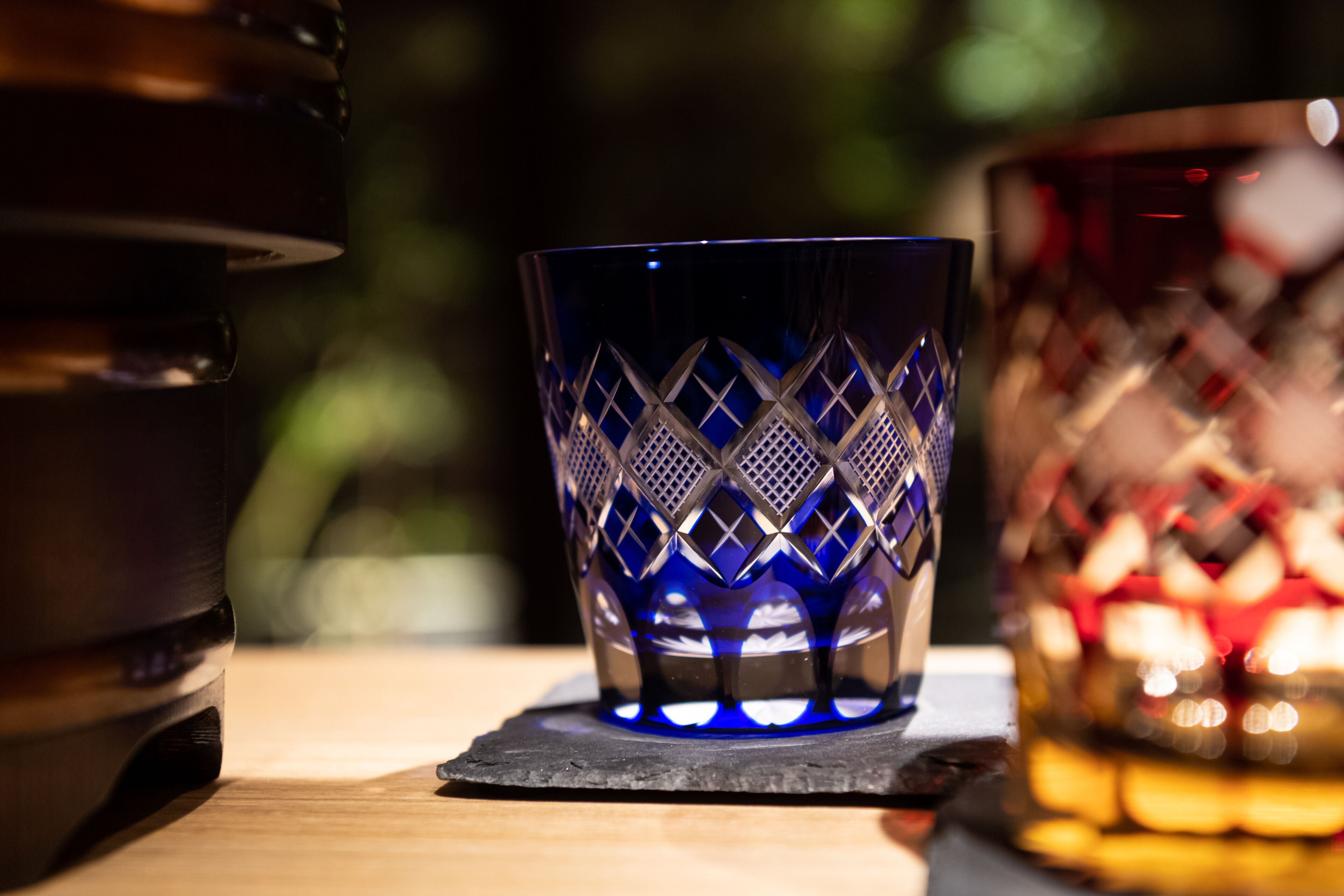 A close-up of a blue glass with a geometric pattern, placed on a dark coaster.