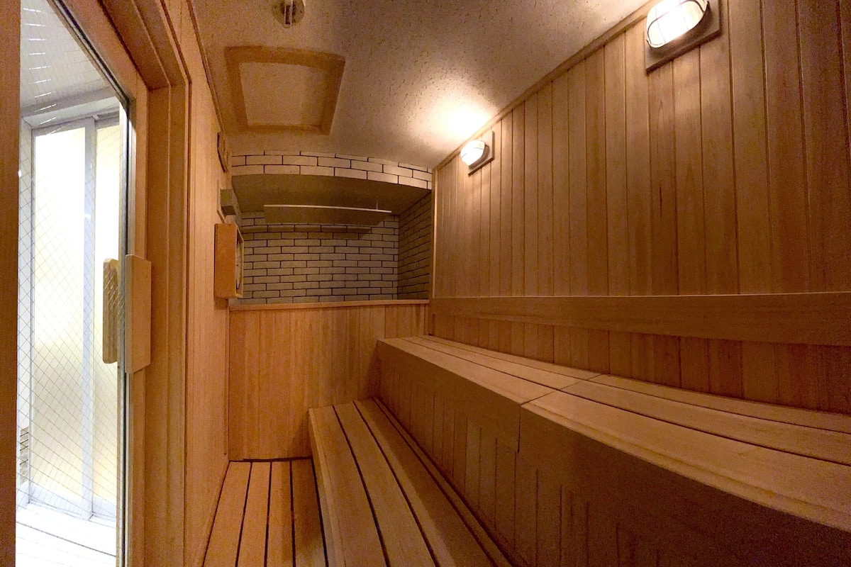A wooden sauna with benches and a brick wall.