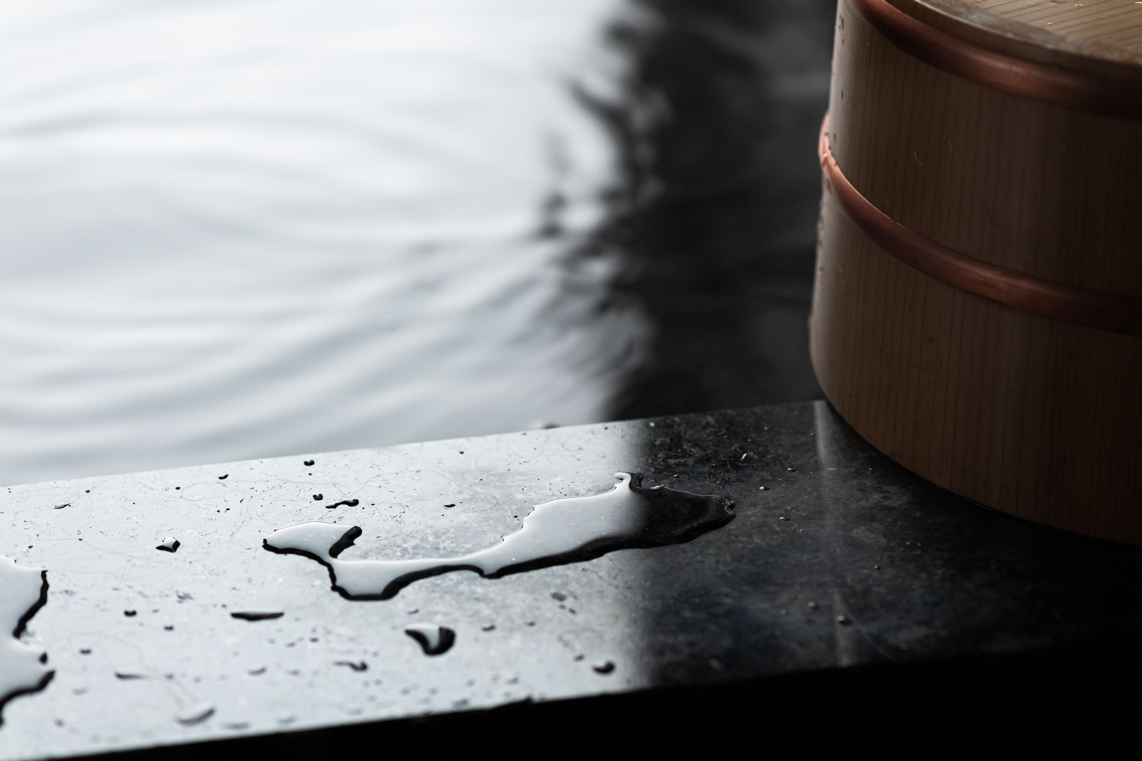 A close-up of a metallic surface with water droplets and a wooden barrel.