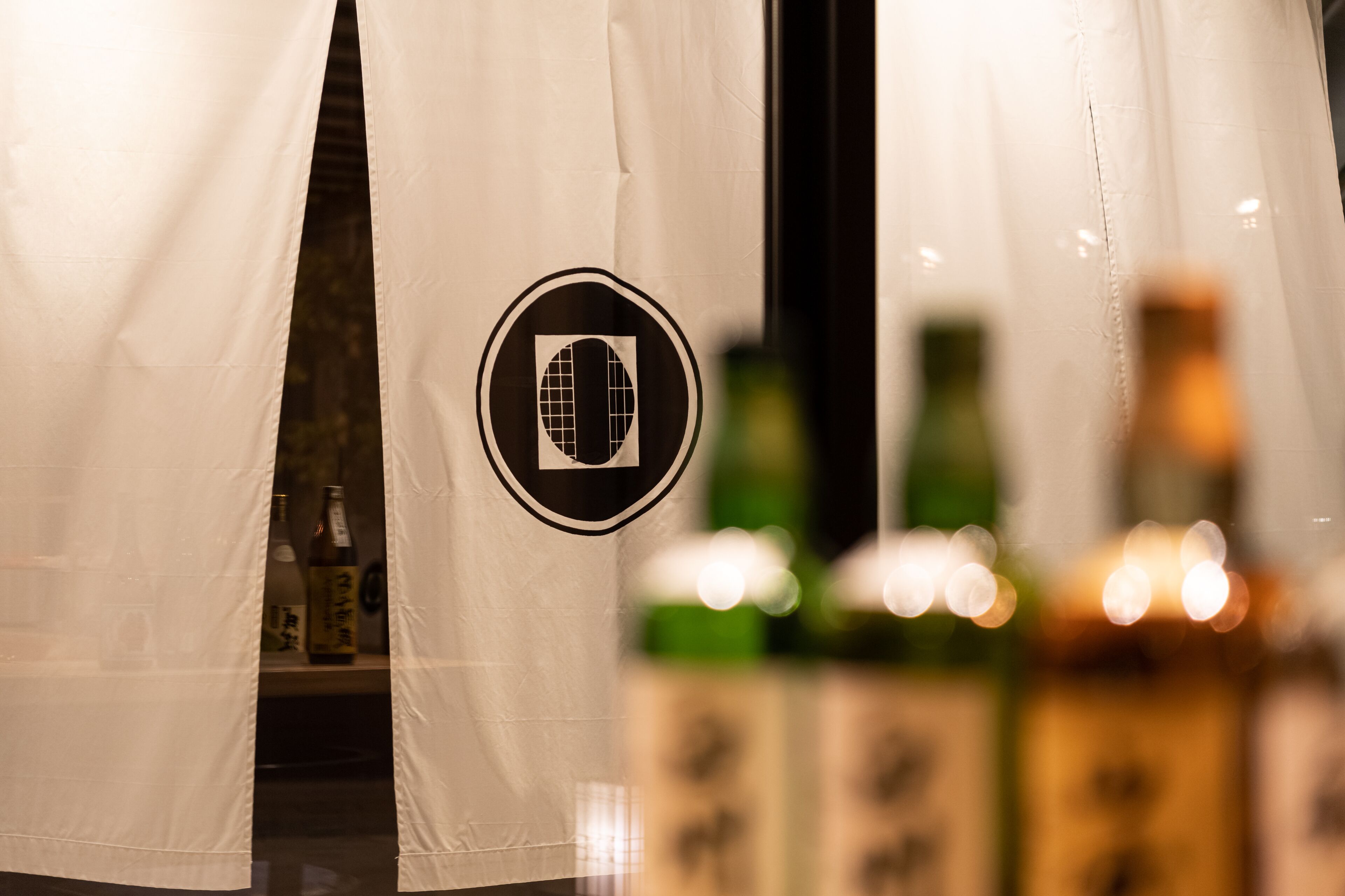A curtain with a logo, a bottle, and a blurred background.