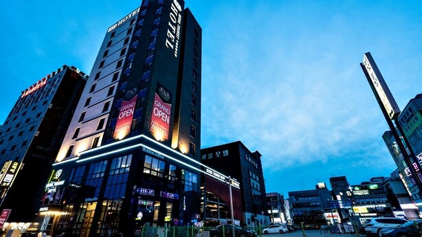 Ett hotell med en tydlig skylt som visar att det är nyöppnat, flera våningar och ett modernt, stadsnära läge.
