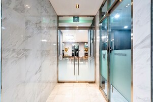 A modern hotel lobby with a marble floor and glass doors leading to a business room.
