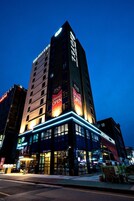 A hotel with multiple floors, illuminated signage, and a prominent 'Grand Open' banner.