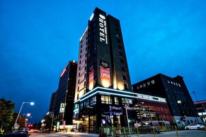 Un hotel con un llamativo letrero de 'Gran Inauguración', varios pisos y una fachada bien iluminada.