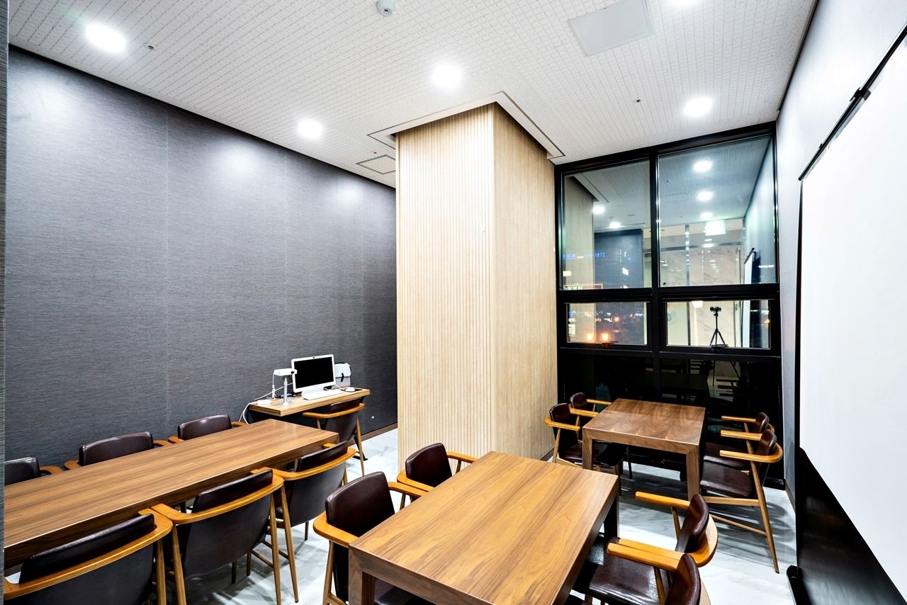 A conference room with wooden tables and chairs, a large window, and a whiteboard.
