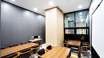A conference room with wooden tables and chairs, a large window, and a whiteboard.
