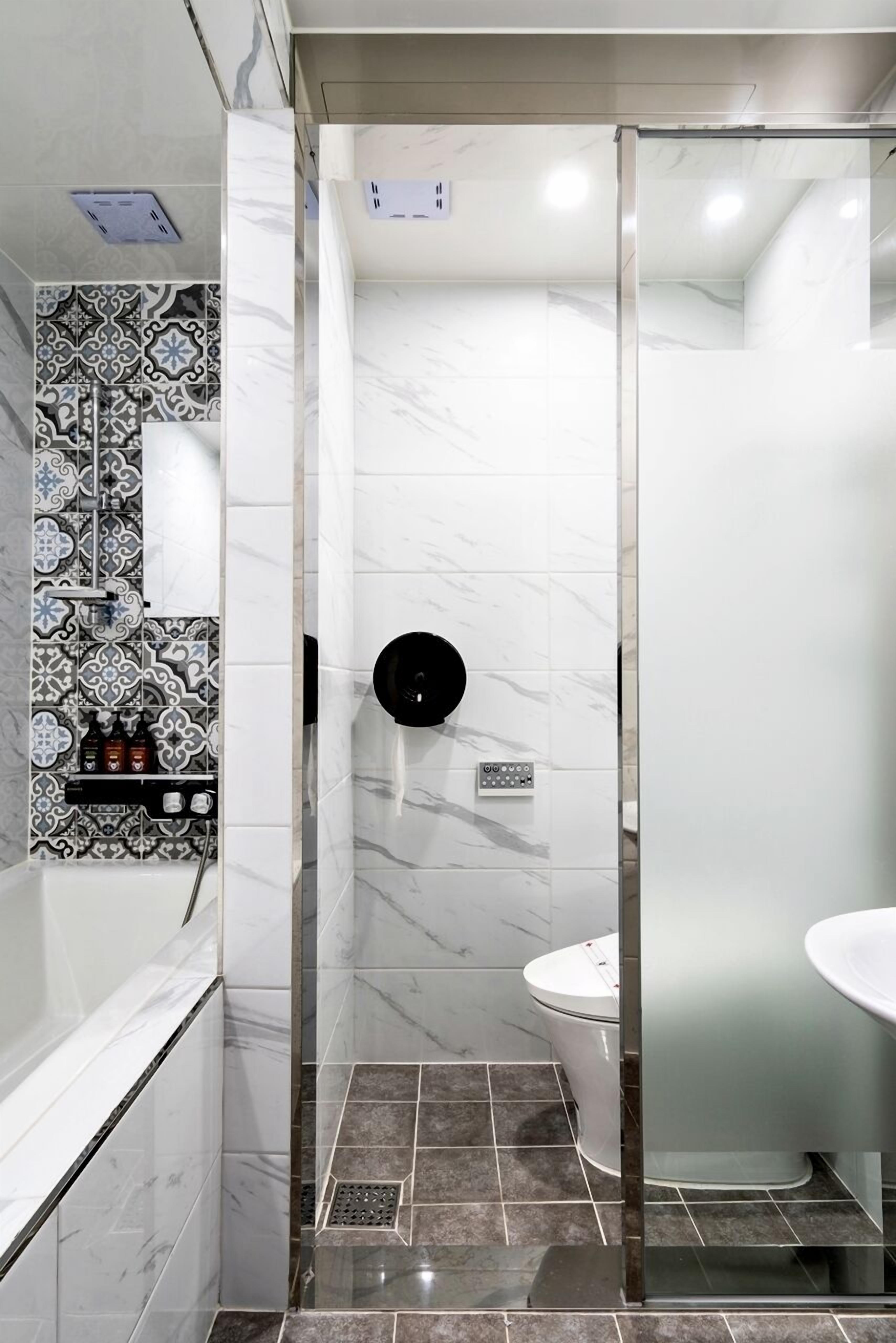 Un baño con cabina de ducha de vidrio, inodoro y lavamanos.