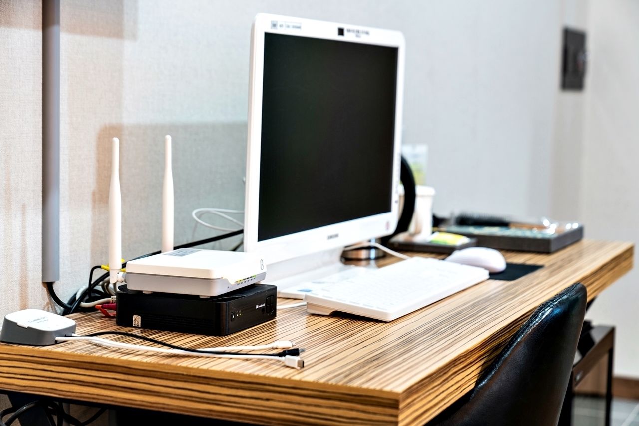 Een houten bureau met een computer, een router en een toetsenbord.