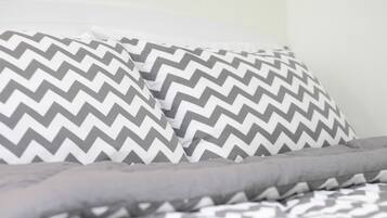 A bed with grey and white patterned bedding.