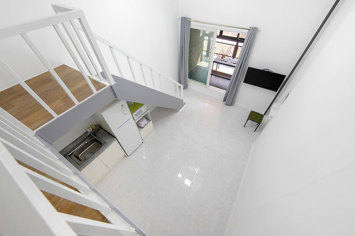 A modern interior with a kitchen, dining area, and a staircase.