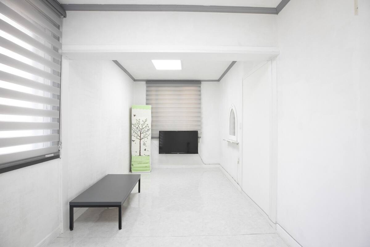 A hallway with a bench, a door, and a window with blinds.