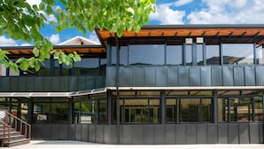 Un bâtiment moderne à deux étages, doté de grandes fenêtres et d’une pergola en bois.