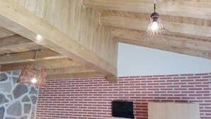 A room with a brick wall, a stone accent wall, wooden beams, and a hanging light fixture.