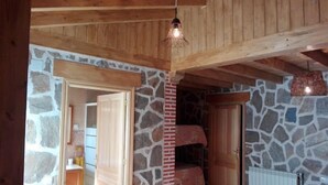 A rustic room with stone walls, a wooden ceiling, and a bunk bed.