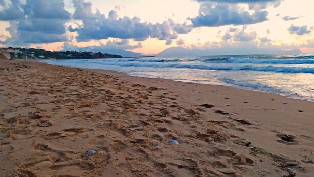 Platja amb empremtes i restes disperses.