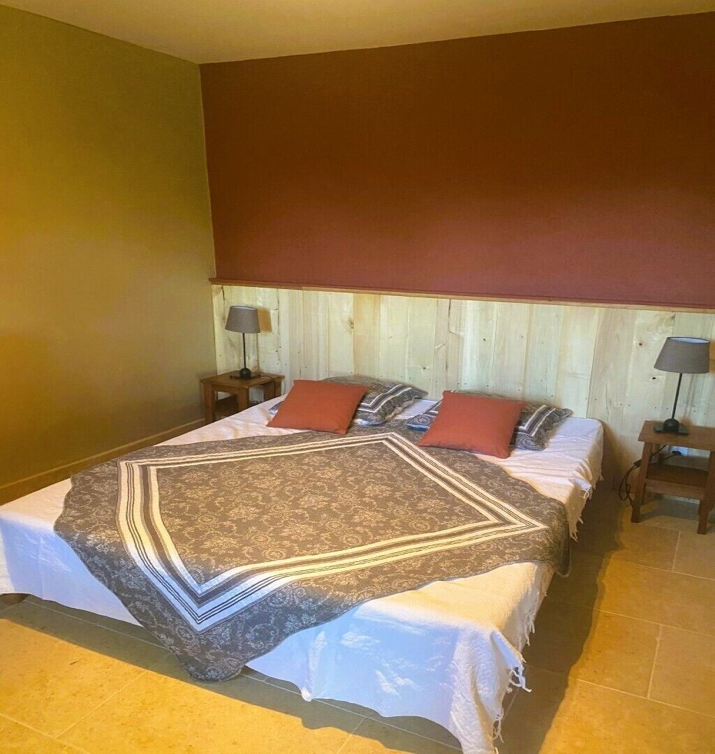 A bedroom with a large bed, two nightstands, and a wooden headboard.