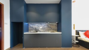 A modern kitchen with dark blue walls, a marble backsplash, and a built-in sink. - BH Riverside Hotel (Hanoi)