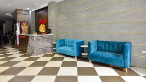 A reception area with a checkered floor, a marble counter, and a blue sofa. - BH Riverside Hotel (Hanoi)