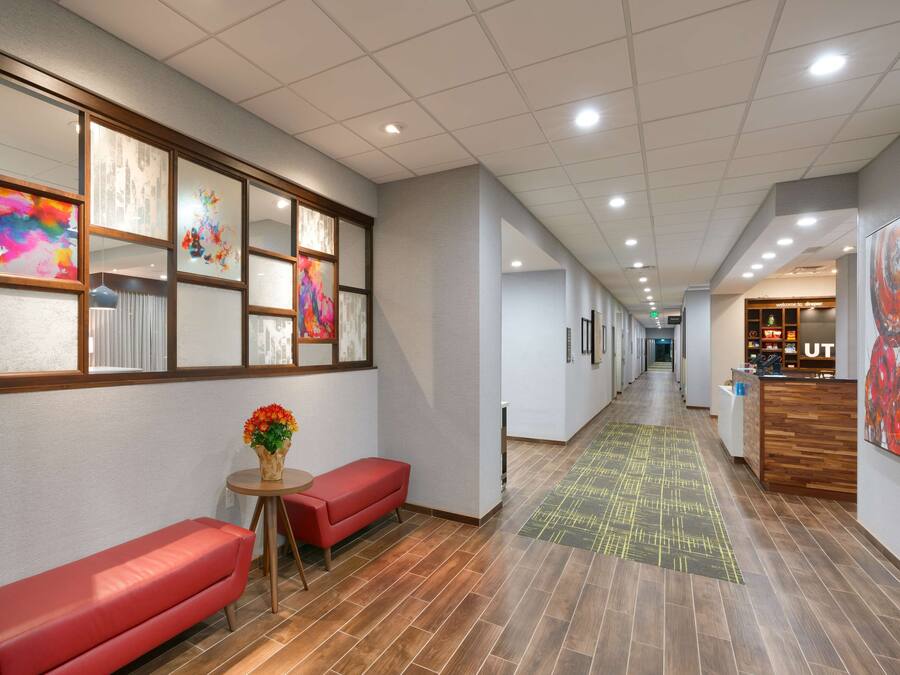 Un passadís d'hotel amb una recepció, una banca vermella i obres d'art a les parets.