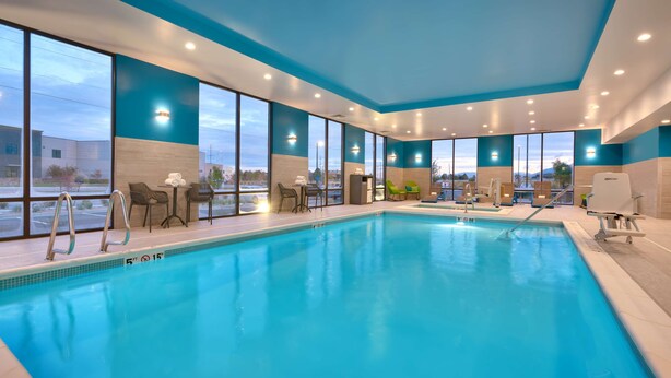An indoor swimming pool with clear blue water, surrounded by large windows offering views of the outside. - Hampton Inn Draper Salt Lake City Ut (Draper)
