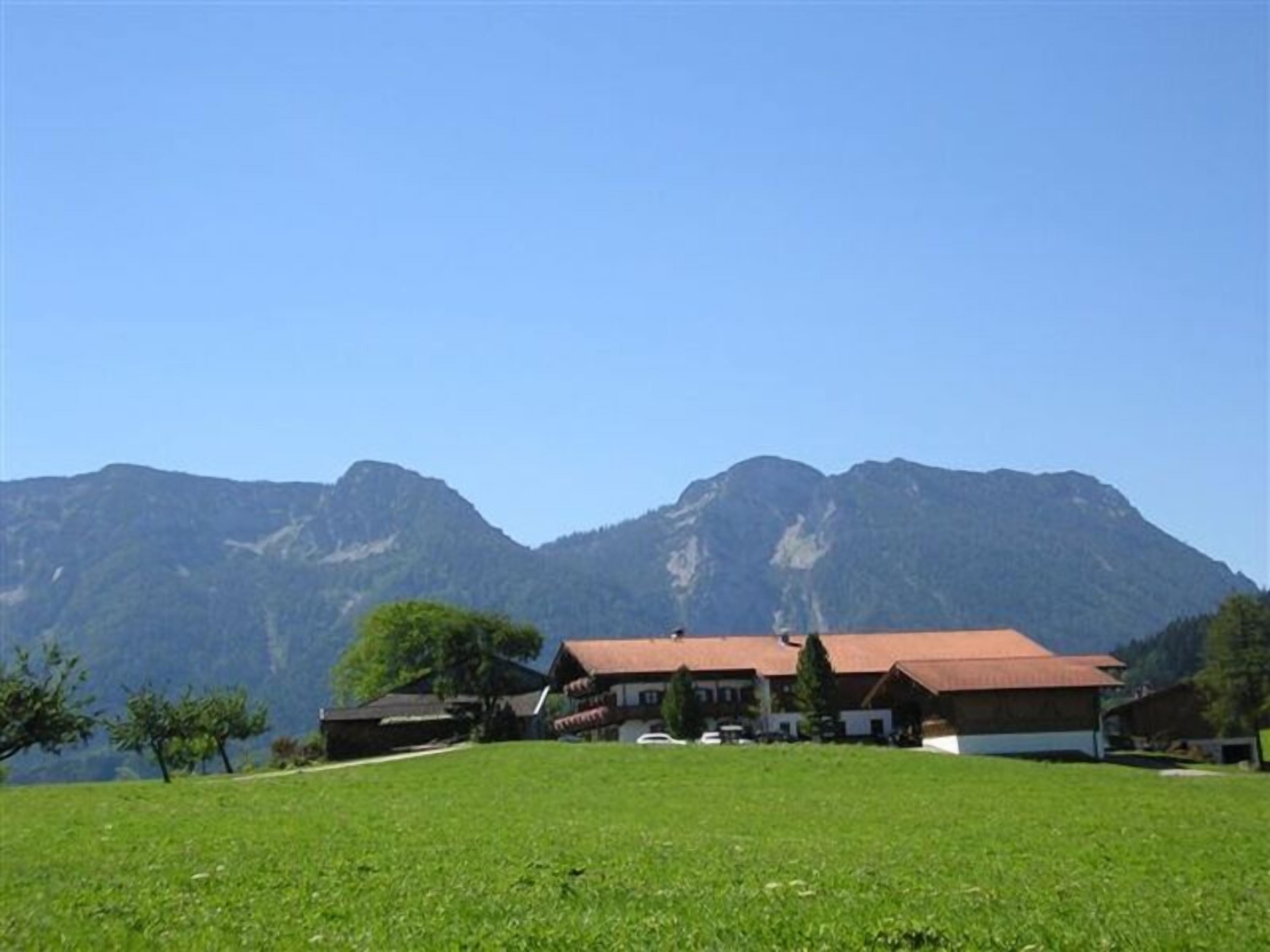 A building with a red roof, surrounded by a grassy field and mountains in the background.
