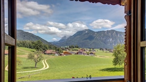 A view from a wooden balcony overlooking a green valley with houses and mountains in the background. - Vacation apartment Hochstaufen for 4 persons, 2 bedrooms, 80 sqm (Inzell)