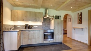 A modern kitchen with wooden cabinets, a built-in oven, and a microwave. - Vacation apartment Hochstaufen for 4 persons, 2 bedrooms, 80 sqm (Inzell)