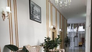 A spacious lobby with a high ceiling, a chandelier, and two beige armchairs with potted plants. - Reikartz Xon Tashkent (Tashkent)