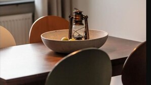 Ein Essbereich mit Tisch, Stühlen, einer Schüssel, einer Laterne und einer Hängelampe.
