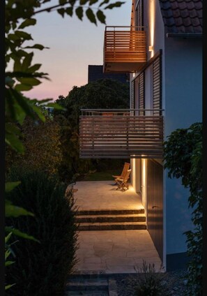 A modern building with a balcony, steps leading to an outdoor seating area, and surrounding greenery. - Fantastic view of the old town of Ochsenfurt (Ochsenfurt)