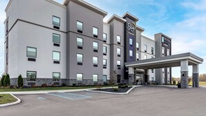 A modern hotel with a central entrance, multiple floors, and a covered parking area.