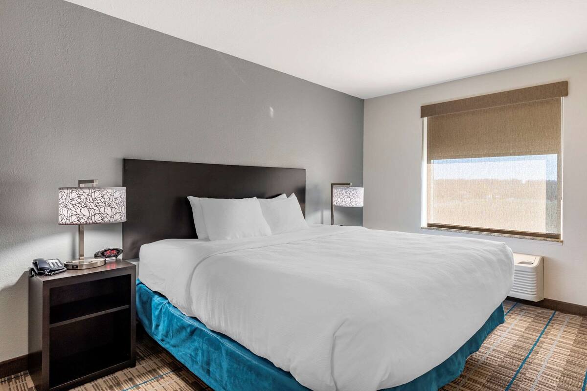 Hotelkamer met een groot bed, twee nachtkastjes, een lamp, een telefoon en een raam met uitzicht.