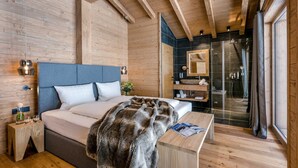 Une chambre dans une cabane en bois, comprenant un lit, une table de chevet et une douche séparée par des parois en verre.