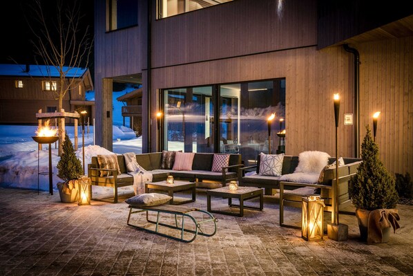 A modern outdoor seating area with sofas, tables, and decorative lanterns.