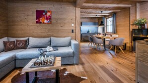 Un intérieur de chalet chaleureux avec un canapé, une table d’échecs et un coin repas.