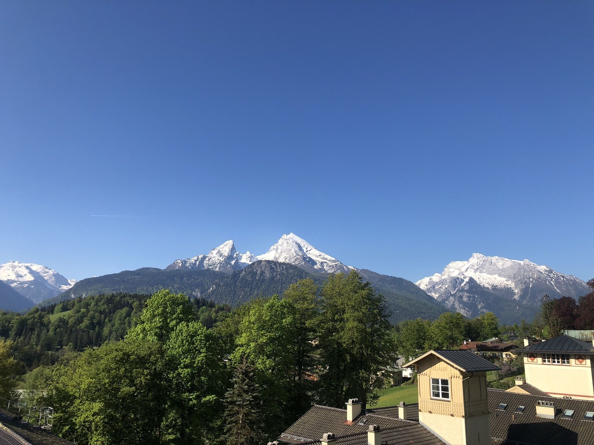 Un paysage de montagne avec des sommets enneigés et une vallée boisée.