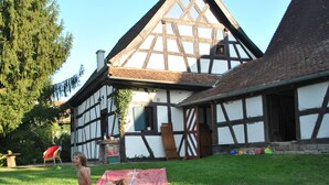 A traditional half-timbered house with a sloped roof, a visible chimney, and a small window.