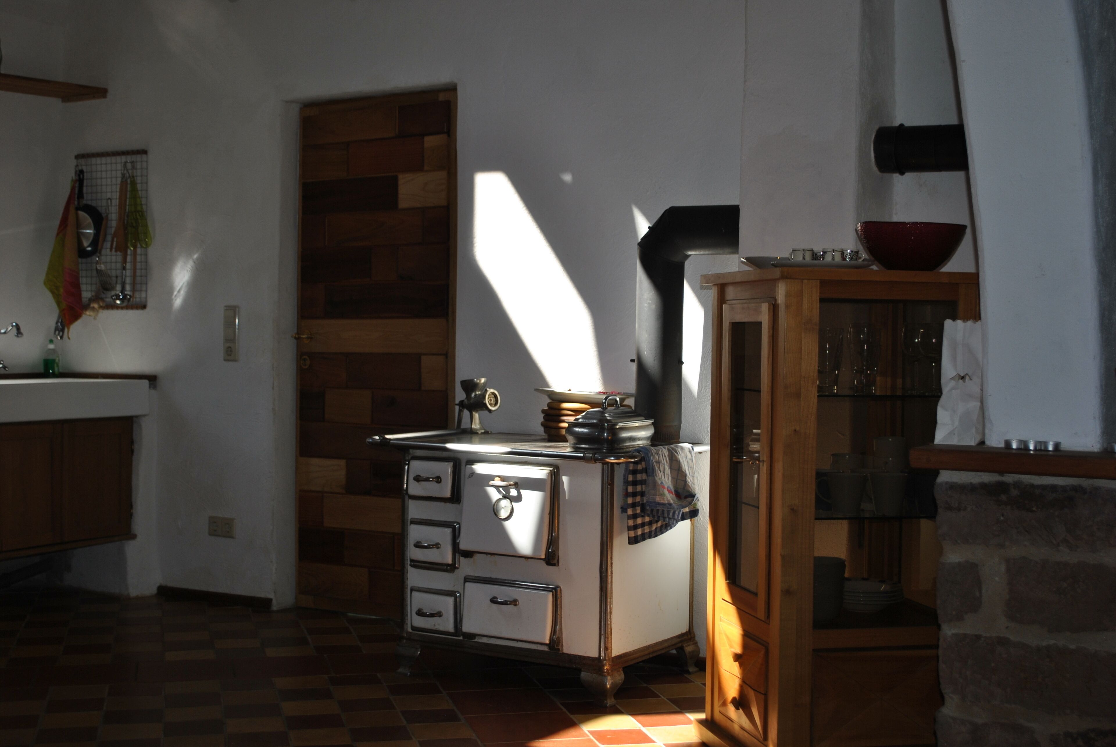 A kitchen with a vintage stove, wooden cabinets, and a stone wall.