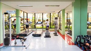 Une salle de sport équipée de tapis de course, de vélos elliptiques et de matériel de musculation.
