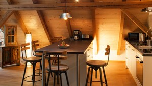 A cozy kitchen with wooden beams, a dining area with four stools, and a large window providing natural light. - Living in a unique atmosphere near the Europapark Rust (Ettenheim)