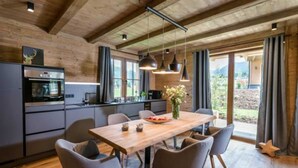 Een moderne keuken met een houten plafond, een eettafel met stoelen en uitzicht op de omgeving.