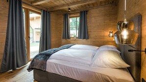 Een houten slaapkamer met een bed, gordijnen en een hanglamp.