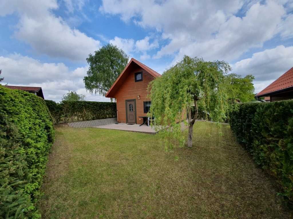 Une maison en bois d’un seul étage, dotée d’un toit à pente, entourée de haies bien entretenues et d’une pelouse verdoyante.