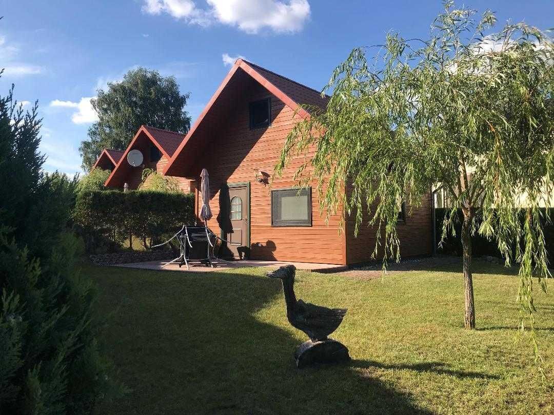Une cabane rustique avec un toit en pente, une petite véranda et une statue d’oiseau au premier plan.