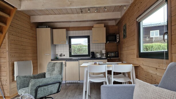 Ett kompakt kök med träskåp, ett matbord och en sittgrupp med en soffa och stolar.